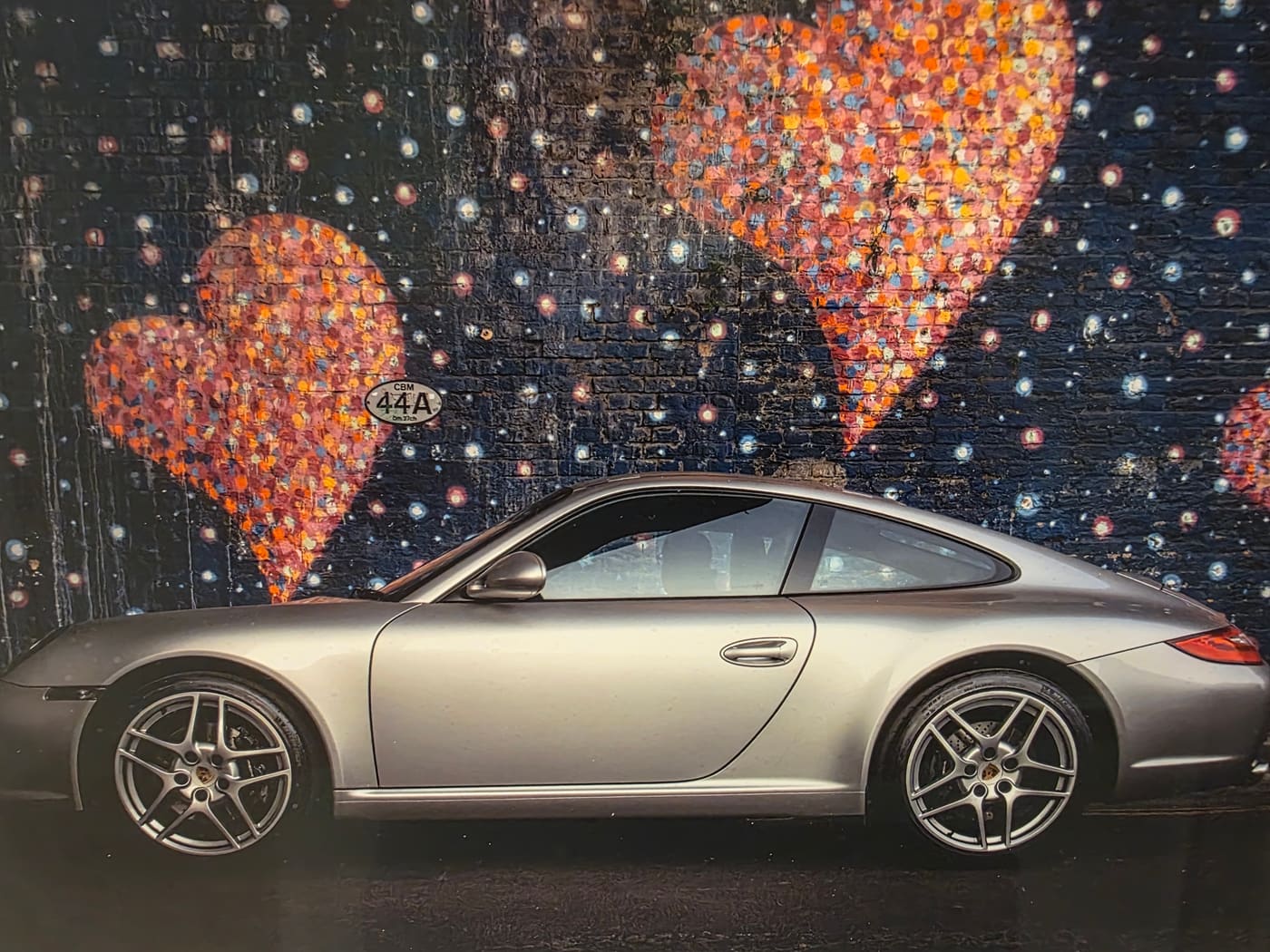 Porsche 911 in front of a heart-covered street-art wall