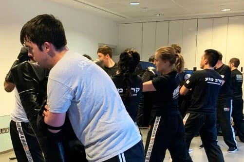 Krav Maga class paired up for pad-work drills